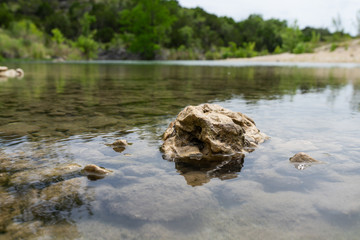 A clear stream flows over a bed of rocks in Texas Hill Country