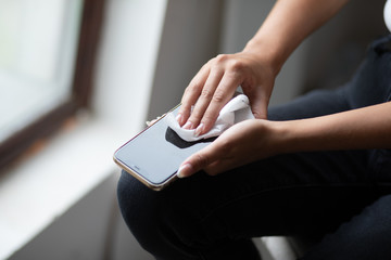 The woman cleans the cell phone with a wet wipes napkin stock photo