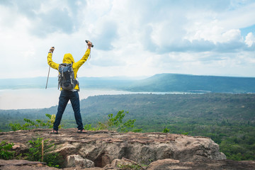 Hikers with backpacks relaxing on top of a mountain and enjoying the view of valley. Young man with...