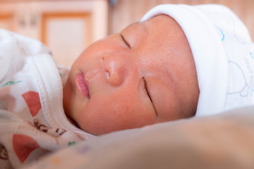 The Sleeping cute New Born Baby infant with hat  on the bed