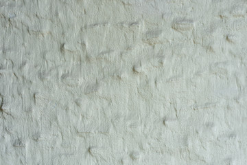 Gray rough cement plaster of the house with protruding stones