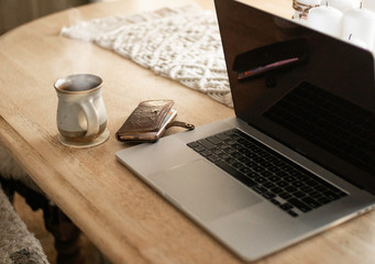 Working from Home with cozy cup of coffee and laptop on dining room table with technology including iPhone.