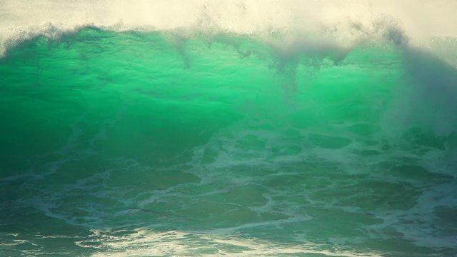 Large emerald ocean wave swell breaking close up in slow motion.