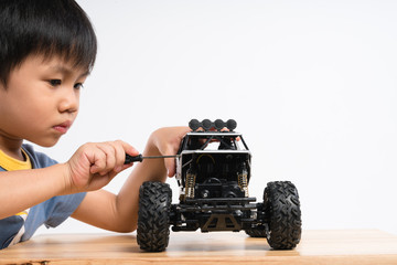 asian boy holding small screw screwdriver to fix car toy on white background