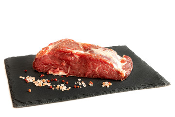 Fresh raw beef steak on a black  slate plate isolated white background.