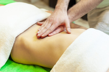 Obraz na płótnie Canvas Side view of hands massaging female abdomen. Therapist applying pressure on belly. Woman receiving massage at spa salon