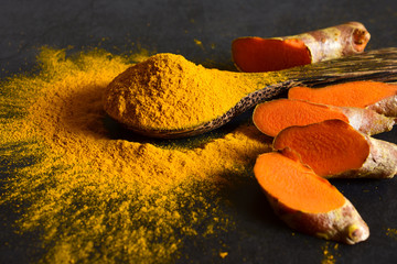 Turmeric powder and fresh turmeric (curcumin) on the black background ,Used for cooking,copy space.