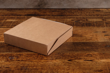 Big brown paper box isolated on wooden background. Eco-friendly disposable food packaging. Preserving nature and recycling concept.Copy space.