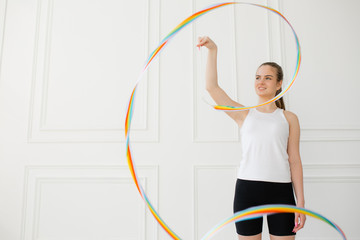 Young girl athlete stands in a bright studio on a white background and performs an exercise circles...