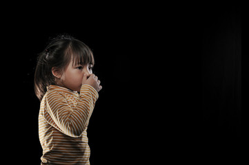 Kid of sneezing, coughing, shocking food concept. A little Asian girl of 5 years old covered nose while sneezing and Causing the water to flow out of the mouth with black background.