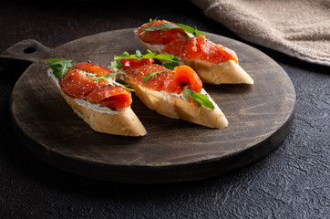 Homemade bruschetta with salmon,cherry tomatoes,fresh arugula and dried pepper.Close up.