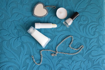 Set of cosmetics for makeup and manicure and jewelry on a turquoise background. The view from the top.