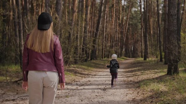 Mother and daughter walk together in the forest. 