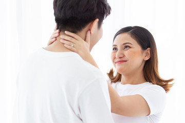 Asian lovely husband and wife portrait, his wife is in pregnancy. Husband tenderly hug and kiss his wife on the bed with care. Husband embracing his pregnant wife and making their hands in heart shape