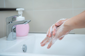 Woman washing her hands by using liquid hand washer soap for protecting from coronavirus 2019,...