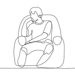 The man sits thoughtfully in an armchair, his right hand props his chin, his left lies freely on the body. A young guy is bored or thinking about something