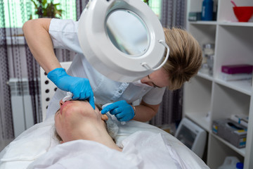 Beautician does facial skin cleansing for his client. Cleansing the skin with special tools. Facial cleansing mask.