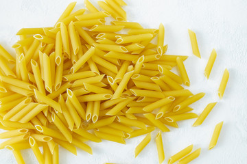 A close-up of penne paste on a light background. Italian cuisine, healthy eating concept. Horizontal orientation, copy space, selective focus, view from above.