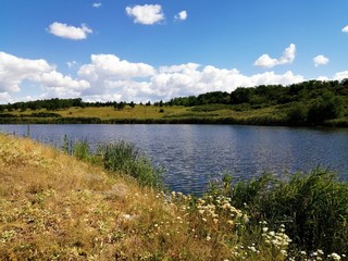 Beautiful summer landscape of a wide lake between hills under a blue sky.