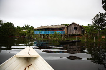 Sailing boat on Amazon jungle river with floating house in front during sunrise  in Brazil