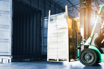 forklift loading large pallet shipment goods into a truck, freight industry delivery logistics and transport, warehouse service cargo export 