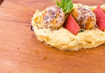 Meat patties or meatballs with millet porridge sprinkled with sesame seeds, decor of red bread and greens on a wooden board, tray.