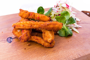 Brush of chicken fillet in tempura flour with blues cheese sauce on a wooden board on a white plate