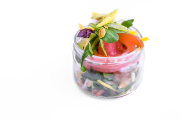 Salad with red fish, citrus fruits, herbs, pumpkin seeds in a glass jar. The object is isolated on a white background.