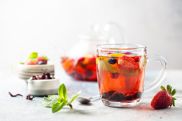Fruit red tea with berries in glass cup on white background