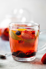 Fruit red tea with berries in glass cup on white background