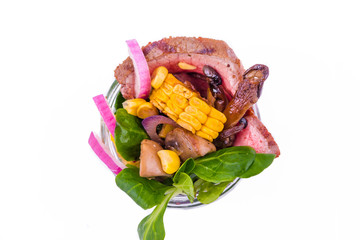 Salad with pieces of beef meat, grilled vegetables - eggplant, corn, mushrooms, sauce in a glass jar on a white background
