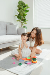 Mother and daughter are doing play a toy and having fun in living room