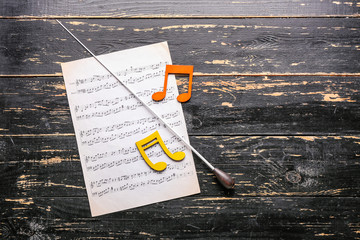 Note sheets and conductor's stick on wooden background