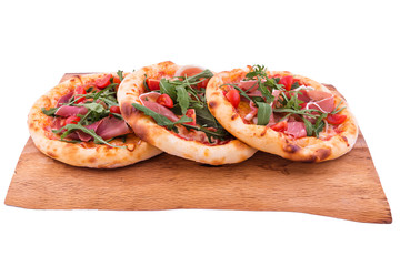 Three pizzas with ham, tomatoes, arugula on a wooden tray. The object is isolated on a white background.