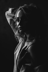 Portrait of a beautiful young blonde woman in low key. Black and white art photo. Soft selective focus.