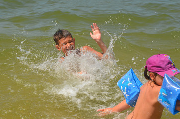 Happy children swimming in the sea. Boy and girl in splashing water summer lifestyle