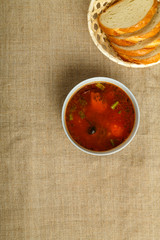 gray plate of italian tomato soup with potatoes and mushrooms linen tablecloth and bread.