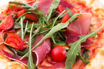 Pizza with ham, tomatoes, arugula and mushrooms close-up