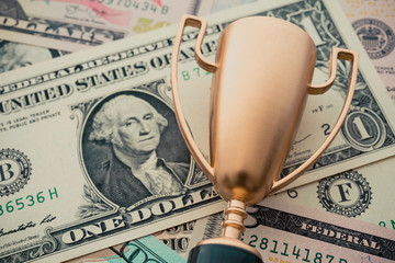Golden champion trophy award on US dollar bill banknotes background. Successful or achieve business...