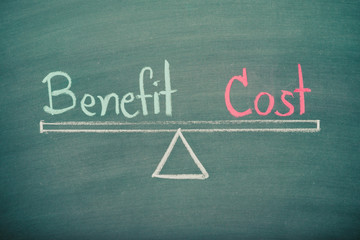 Obraz premium Text word benefit and cost balance on seesaw drawing writing on chalkboard or blackboard background. Concept of benefit and cost analysis in business, financial and investment. Real photo.