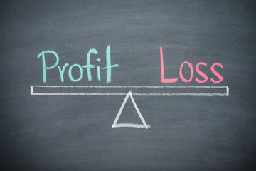Text word profit and loss balance on seesaw drawing writing on chalkboard or blackboard background. Concept of profit and loss analysis in business, financial and investment. Real photo.