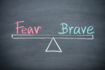 Text word fear and brave balance on seesaw drawing writing on chalkboard or blackboard background....