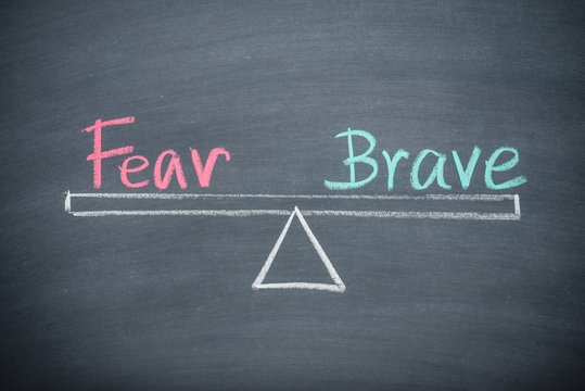 Text word fear and brave balance on seesaw drawing writing on chalkboard or blackboard background. Concept of fear and brave emotion in business, financial and investment. Real photo, not illustration