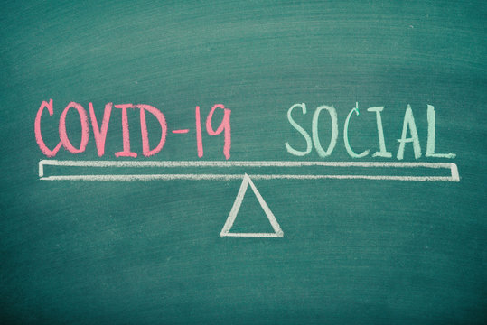 Text word COVID-19 and Social balance handwriting on seesaw drawing on blackboard or chalkboard background. Social diatancing to protect coronavirus crisis impact to global. Healthcare concept.