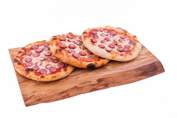 Three tasty pepperoni pizzas. Top view of hot pepperoni pizzas on a wooden tray, board, dish. The object is isolated on a white background.