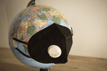 Globe wear medical face mask on wooden table white wall background. Global novel coronavirus...