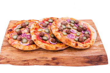 Tasty pizza with meat balls, onions, pickled cucumber on a wooden tray. The object is isolated on a white background.