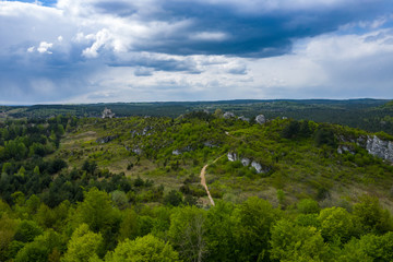 Obraz premium Aerial view of limestone rock formations in green located near Krakow in Poland. Shots from the drone showing the vast green hilly areas of the Cracow-Częstochowa highlands. Kraków-Częstochowa Jura.