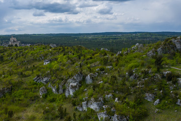 Fototapeta na wymiar Aerial view of limestone rock formations in green located near Krakow in Poland. Shots from the drone showing the vast green hilly areas of the Cracow-Częstochowa highlands. Kraków-Częstochowa Jura.