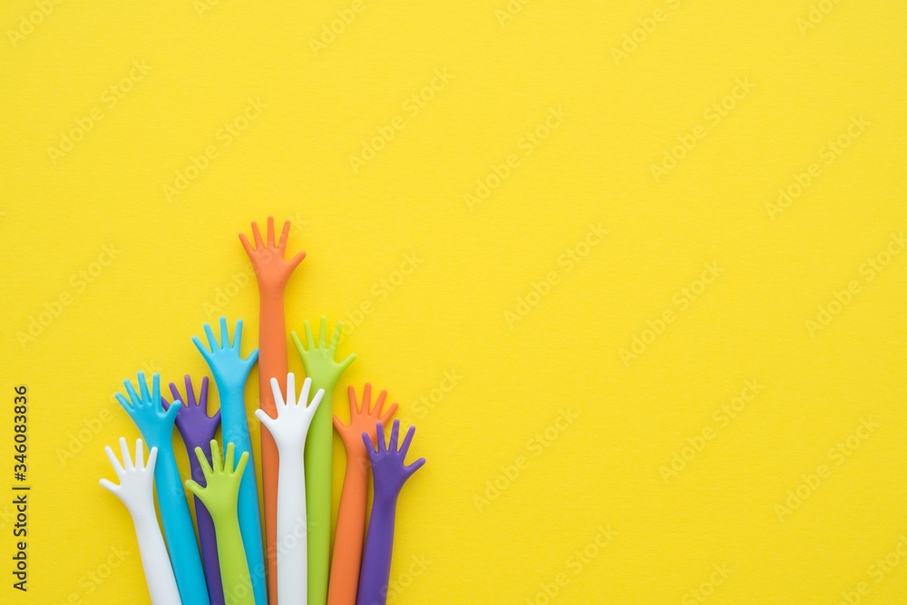 Wall mural Many colorful hands up on yellow background with copy space. Concept of international human rights, equality and peace. Color hands are symbol of diversity.